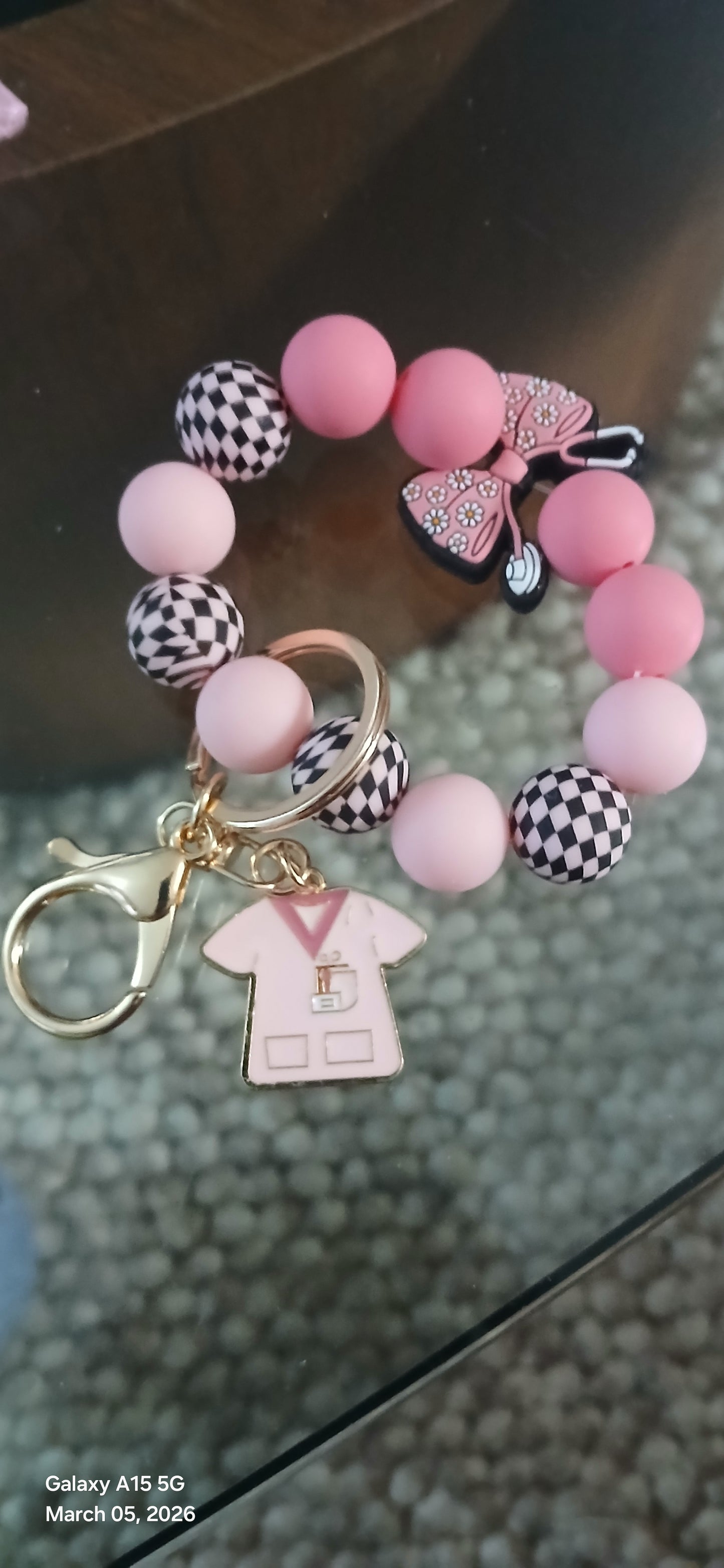 Pink beaded bracelet with decorative elements on a reflective surface