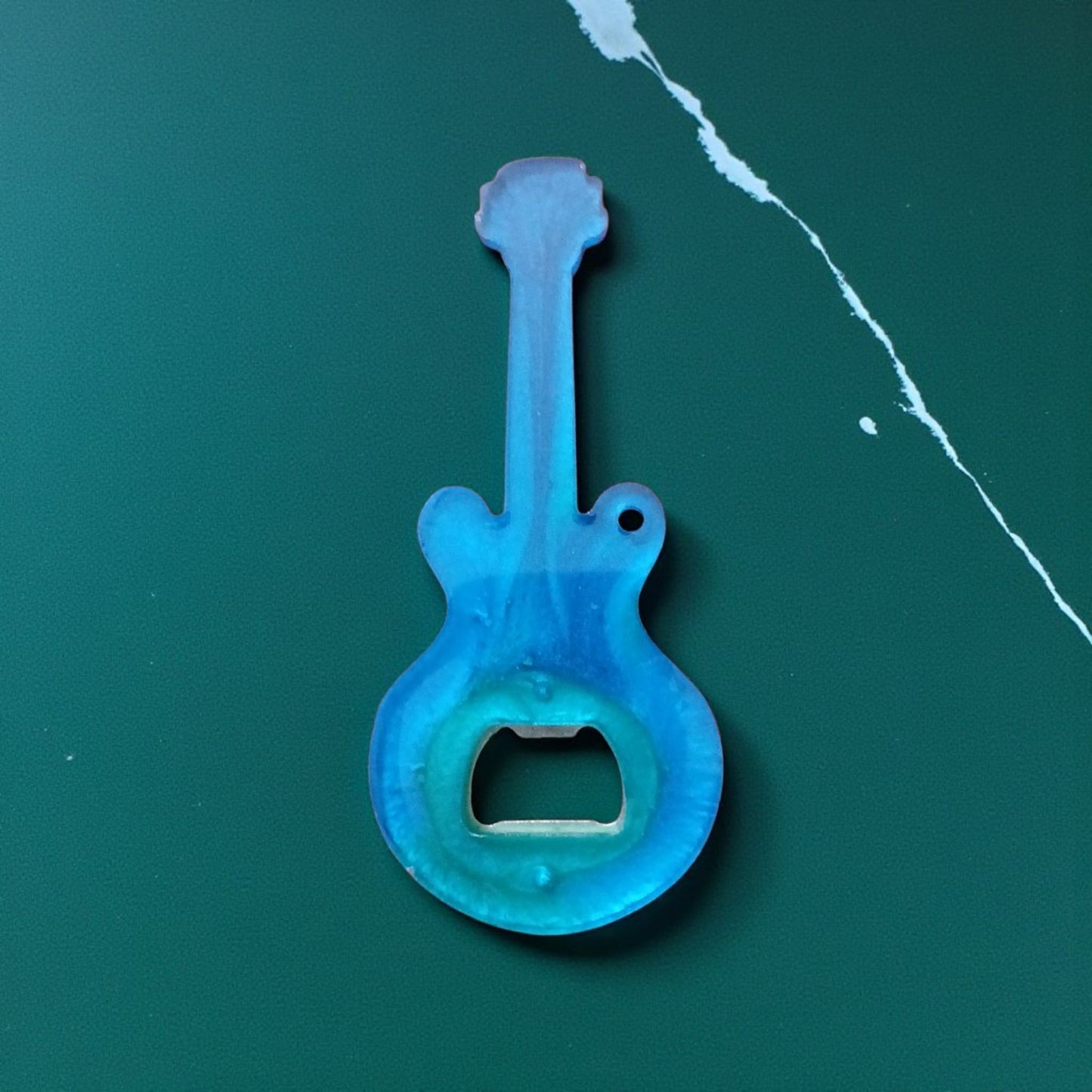 Blue guitar-shaped bottle opener on a green background