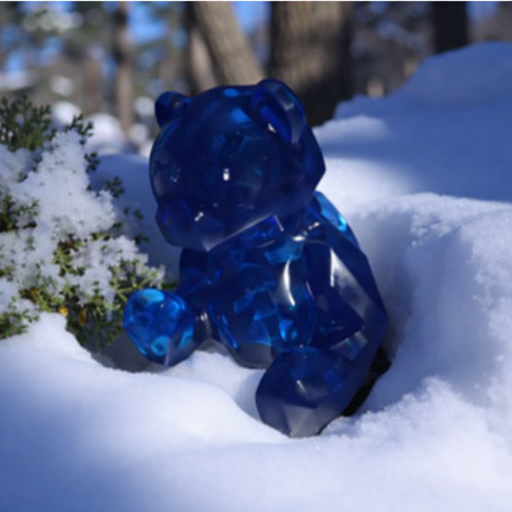 Blue gummy bear toy in the snow with a blurred natural background