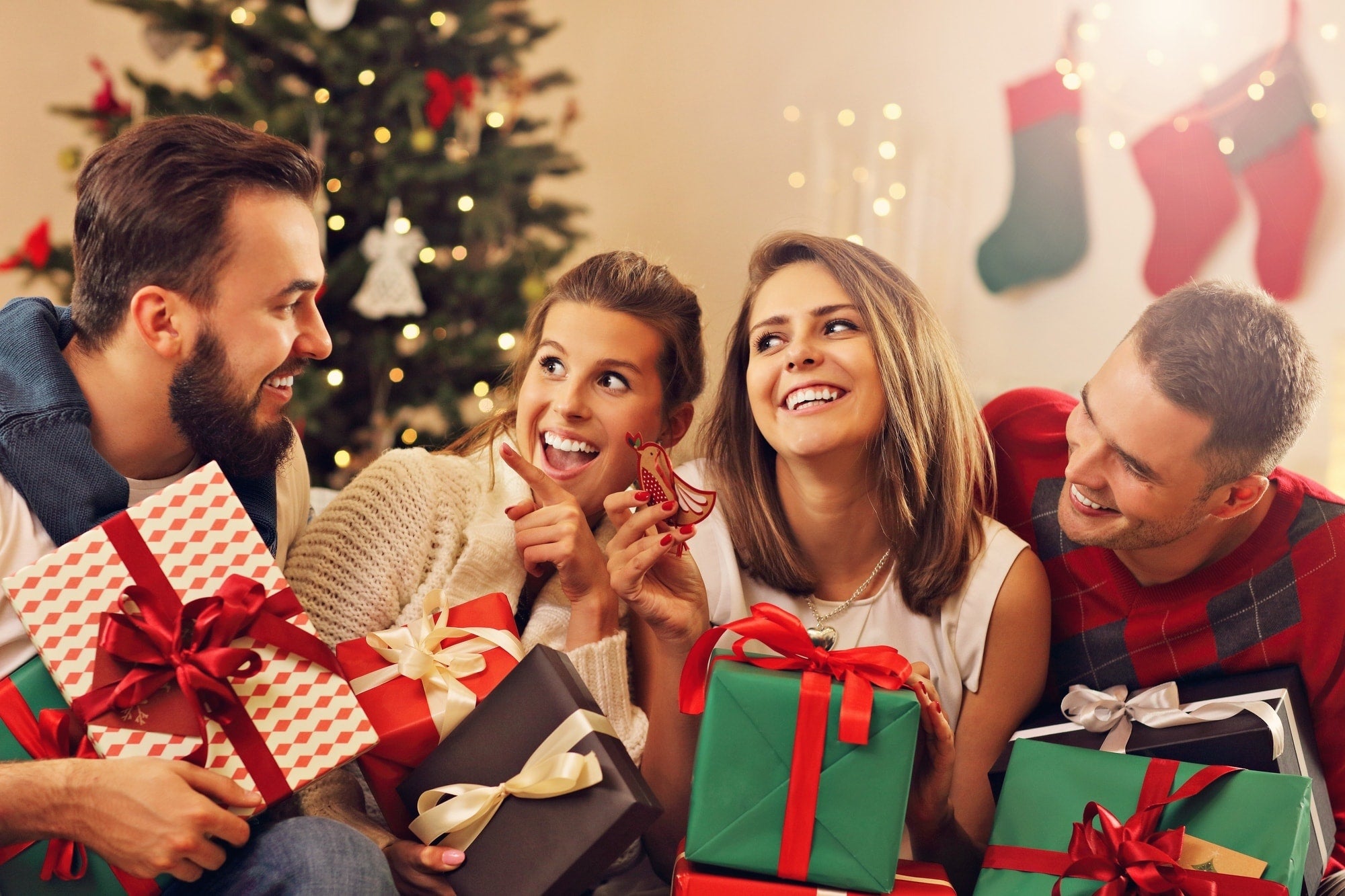 Four people gathered together with Christmas presents in a festive setting.
