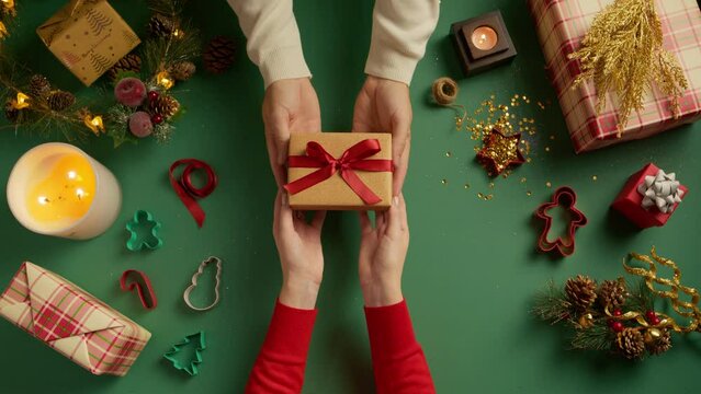 Two pairs of hands exchanging a gift with a festive green background.