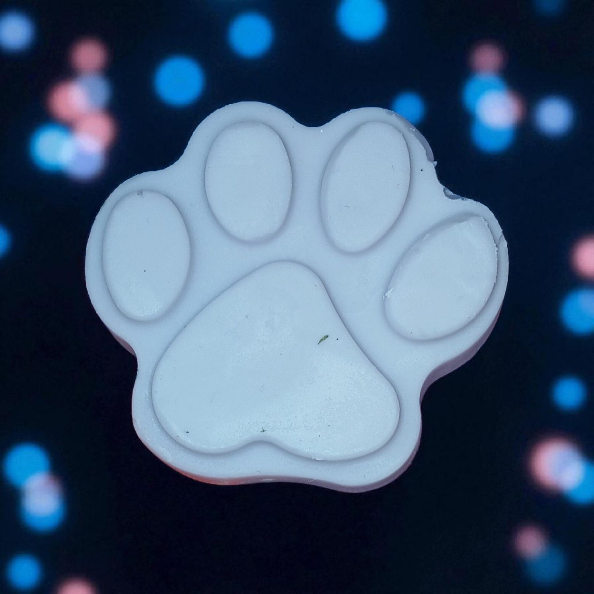 White paw print shape on a dark background with colorful bokeh lights