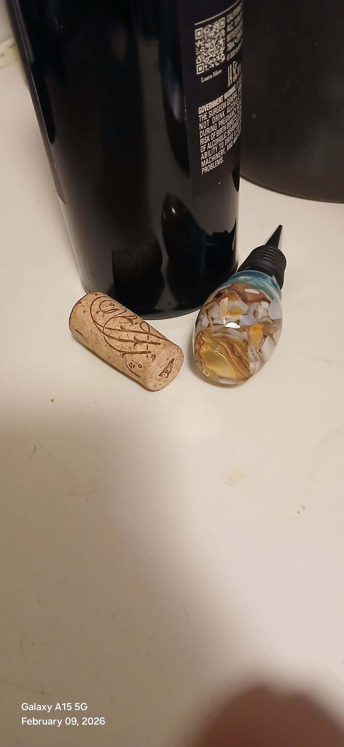 Black bottle with cork and label on a white surface