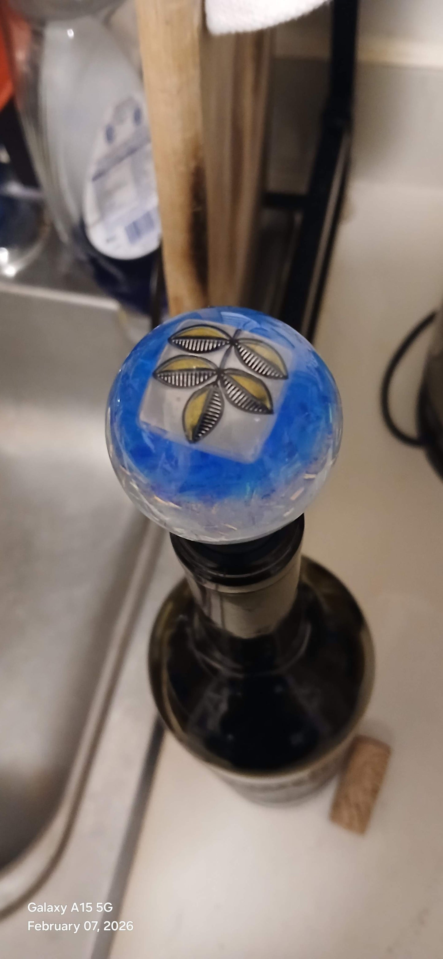Close-up of a wine bottle cap with a decorative design on a kitchen counter.