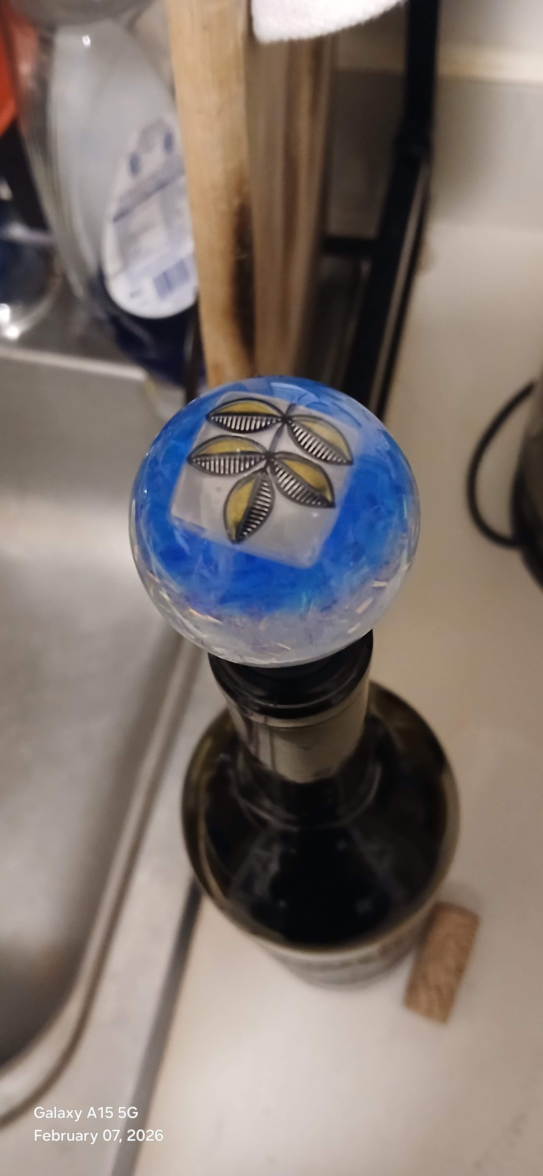 Close-up of a wine bottle cap with a decorative design on a kitchen counter.