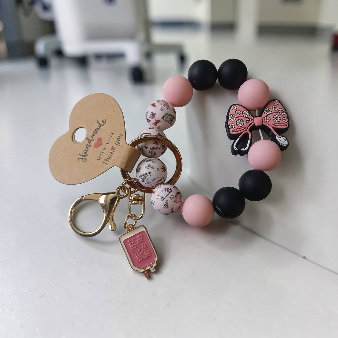 Bracelet with pink and black beads and a keychain on a white surface