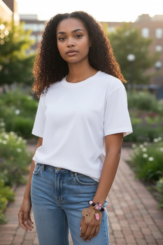 Woman wearing a white t-shirt and blue jeans standing outdoors with greenery in the background