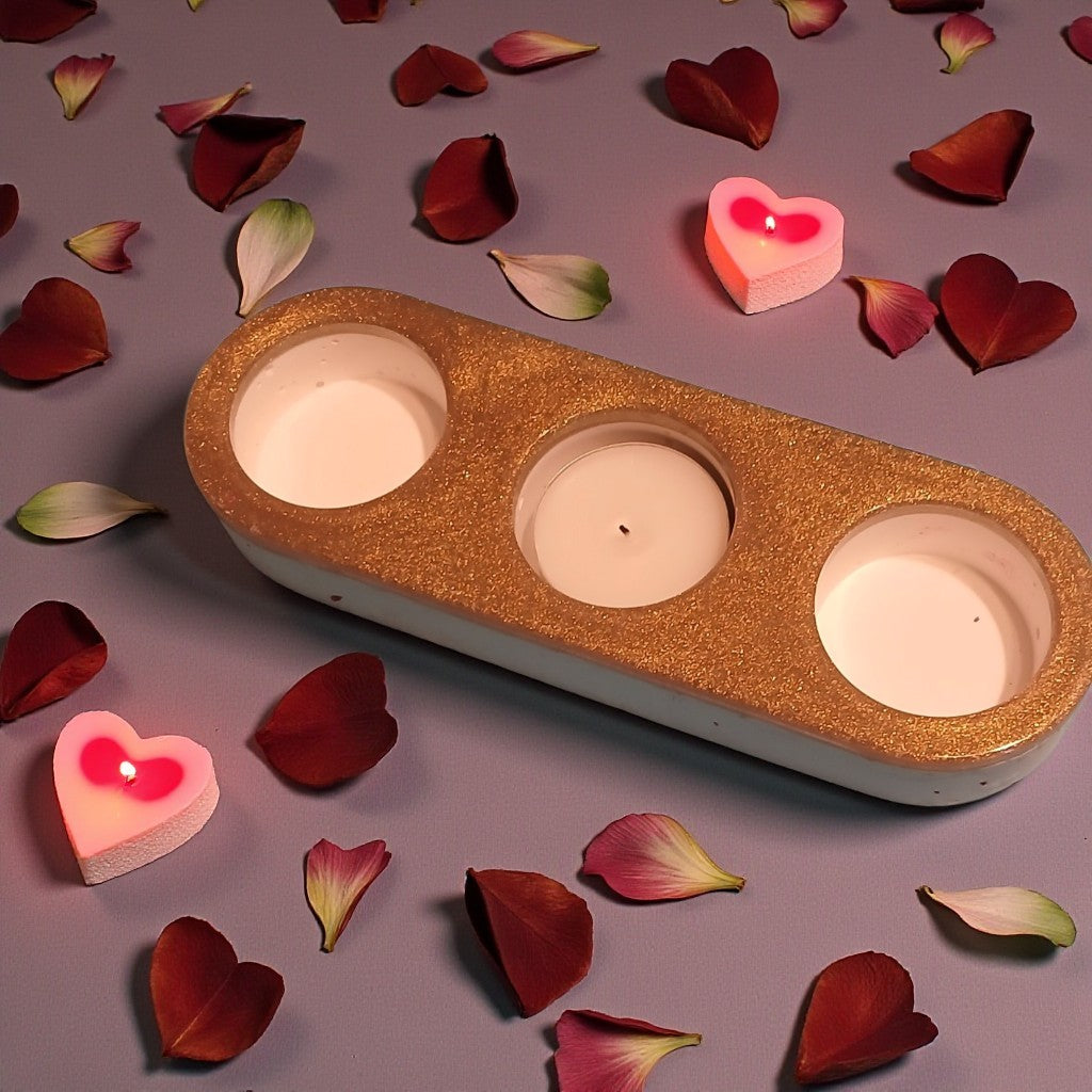 Three-wick candle holder with heart-shaped candles on a surface with red and pink petals.