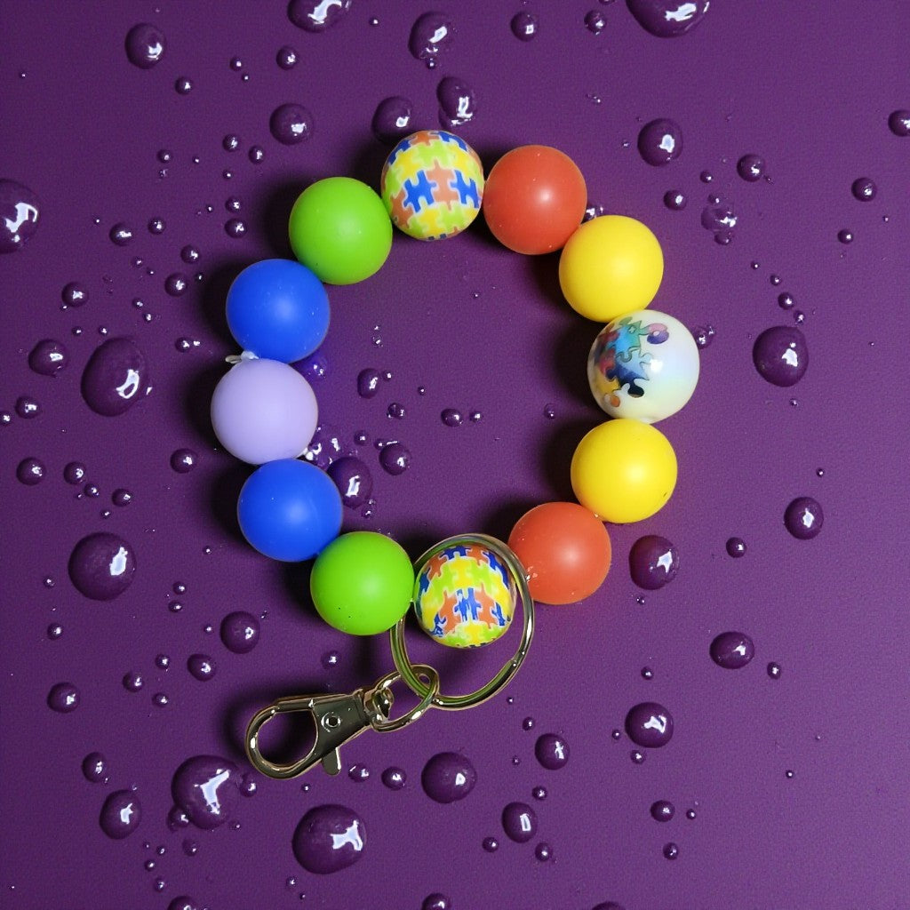 Colorful bubble gum ball keychain on a purple surface with water droplets
