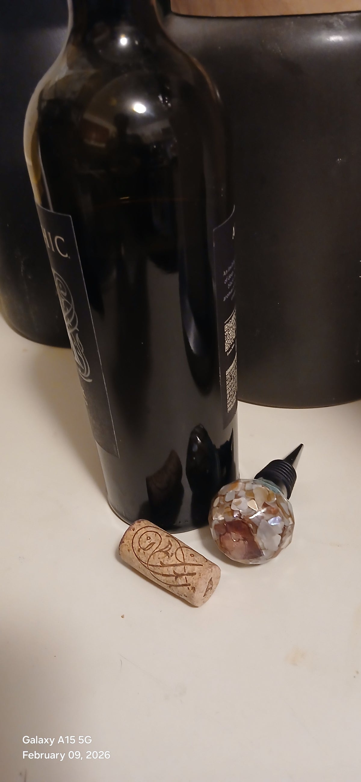 Open bottle of red wine with a cork on a white surface