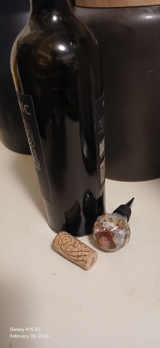 Open bottle of red wine with a cork on a white surface